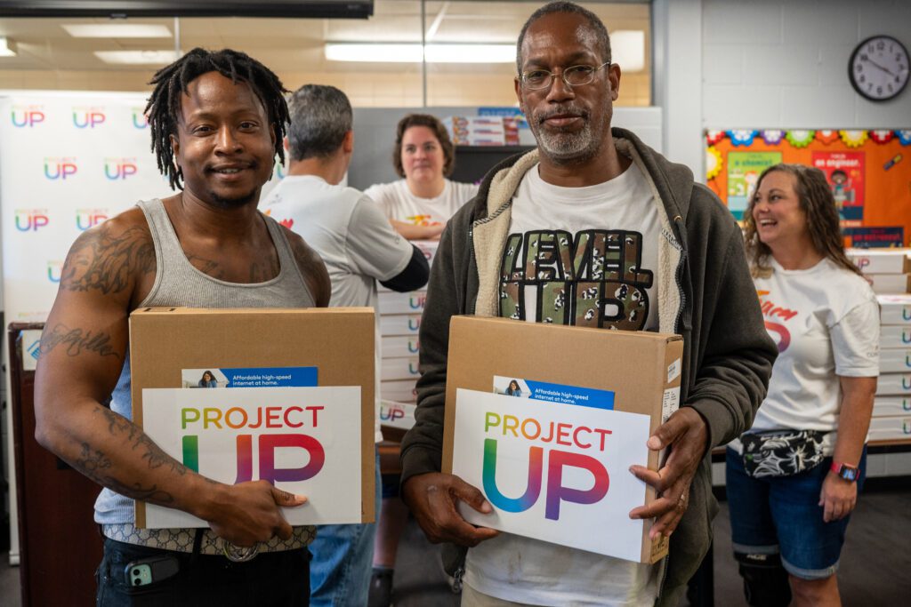 Two laptop recipients smile at the camera.