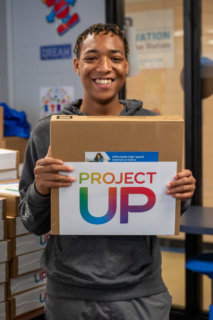 A laptop recipient smiles at the camera.