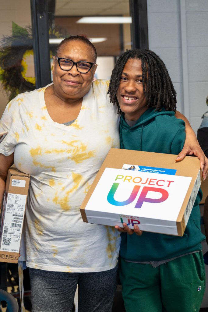 Two laptop recipients smile at the camera.