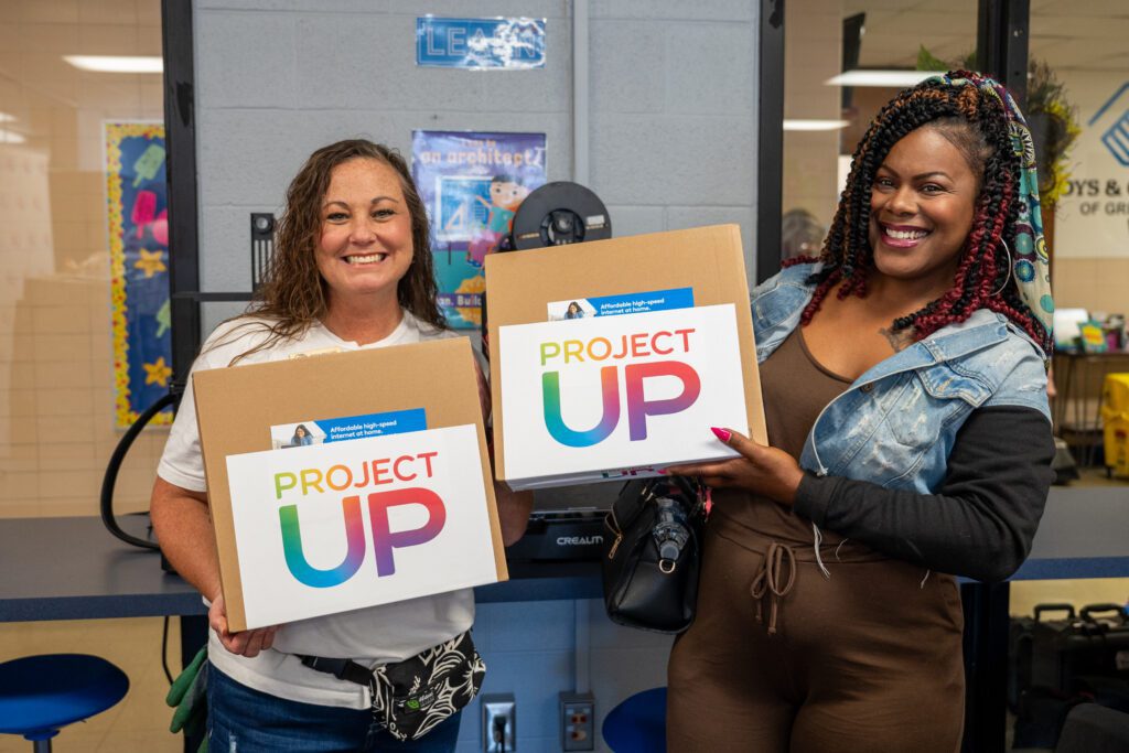 A laptop recipient smile at the camera with Kim Vernon, Comcast Sr. Manager, Human Resources.