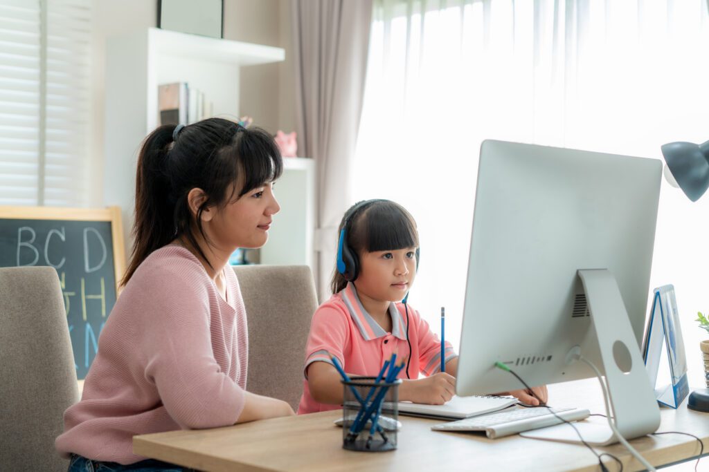 Mom with young student explore the world of e-learning for academic success and bridge the digital divide for National Online Learning Day.