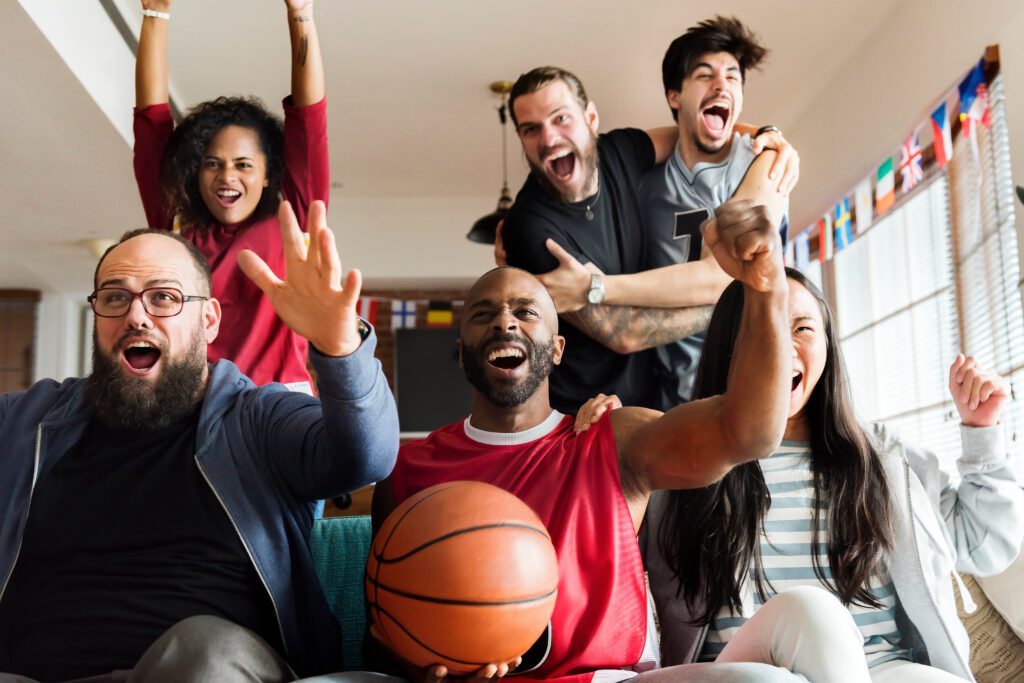 A group of fans are watching basketball on a couch. March Madness fans are not only watching multiple games with Xfinity Multiview but keeping up with their March Madness brackets and scores only with Xfinity.