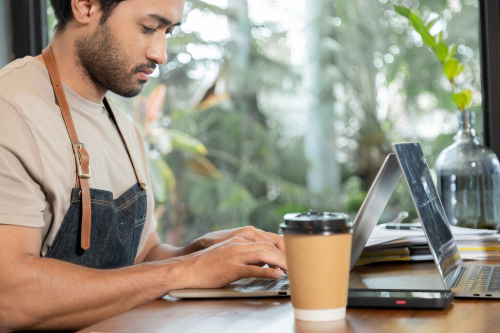 Small businesses in Michigan utilize Comcast Business to run their organization with fast, secure and reliable Internet and power their mobile devices. IMAGE: Attractive barista male or employee concentrate on stacks of tax declaration bills, restaurant owner using laptop for bookkeeping control payment, multitask small business lifestyle doing everything